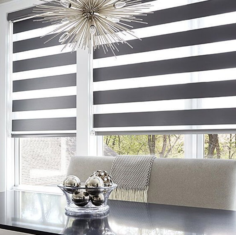 Комната с большими пластиковыми окнами белого цвета с установленными рулонными жалюзи типа День-Ночь.