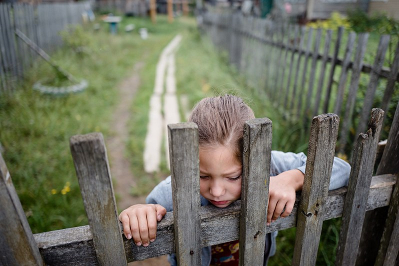 A girl leans on her home's fence, Koynas village, Leshukonsky district, Arkhangelsk region, Russia. August 2017