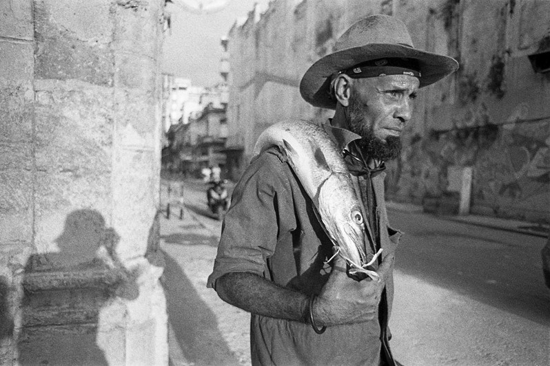 Self-portrait and portrait of a fisherman with a barracuda on Anima street, Centro Habana district, Havana, Cuba. 2022