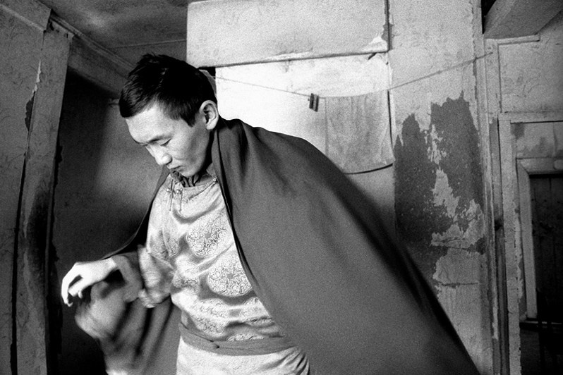 Buddhist monk dressed in traditional dress, prepares to join other students at a temple of meditation, Verkhnyaya Ivolga village, Buryatia, Russia. November 2001