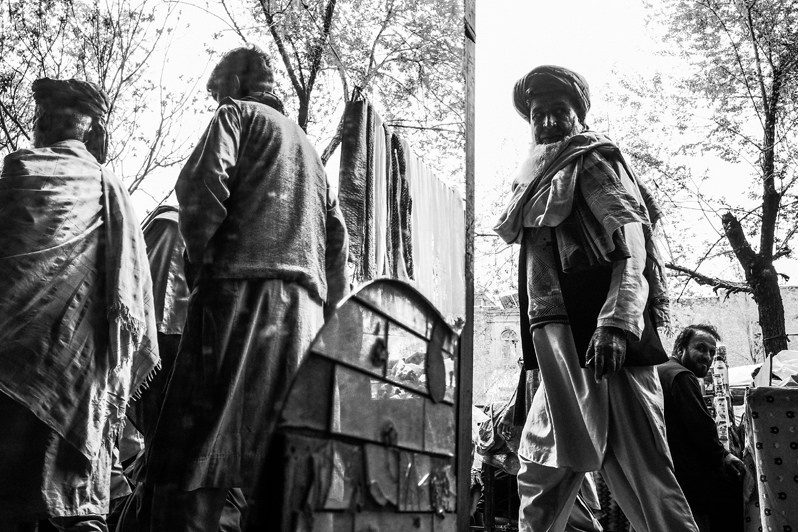 Curious passers-by peer into the shop after spotting a foreign woman there, Kabul, Afghanistan. 2024