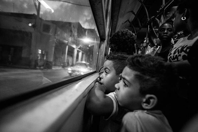 Two children fantasise at the window of a bus travelling on route P11, Reina street, Centro Habana district, Havana, Cuba. 2016