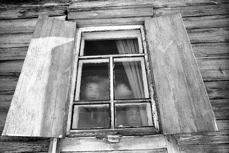 Portrait of two Buddhist monks in the window of their dwelling, Verkhnyaya Ivolga village, Buryatia, Russia. November 2001
