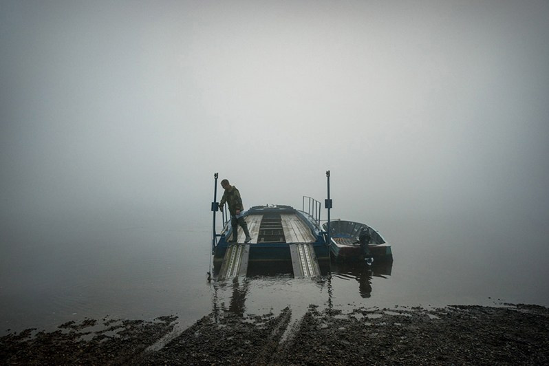 A man prepares a small ferry adapted for car transport, near Vozhgora village, Leshukonsky district, Arkhangelsk region, Russia. August 2017