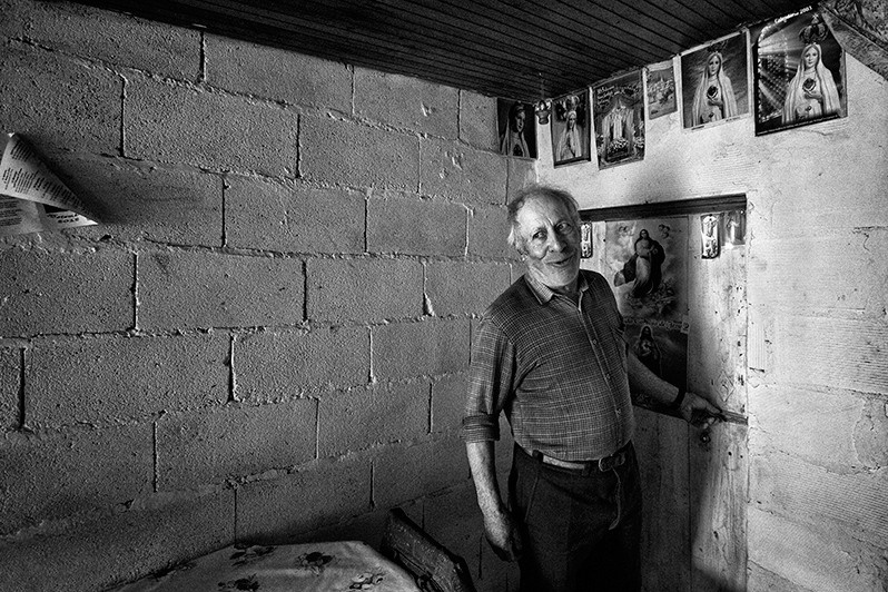 Man opens the door of a room in his house while telling a joke, Boticas municipality, Vila Real district, Trás-os-Montes region, Portugal. 2013