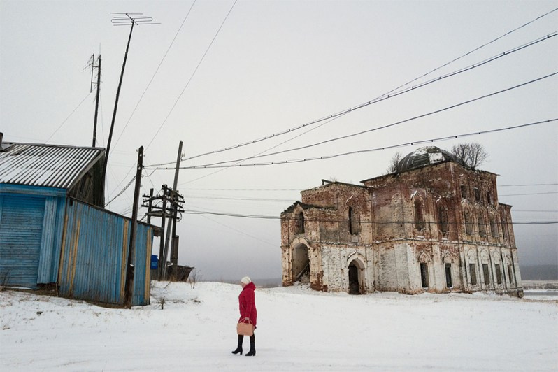 A teacher walking home after school past old church ruins, Glotovo village, Udorsky district, Komi Republic, Russia. 2018
