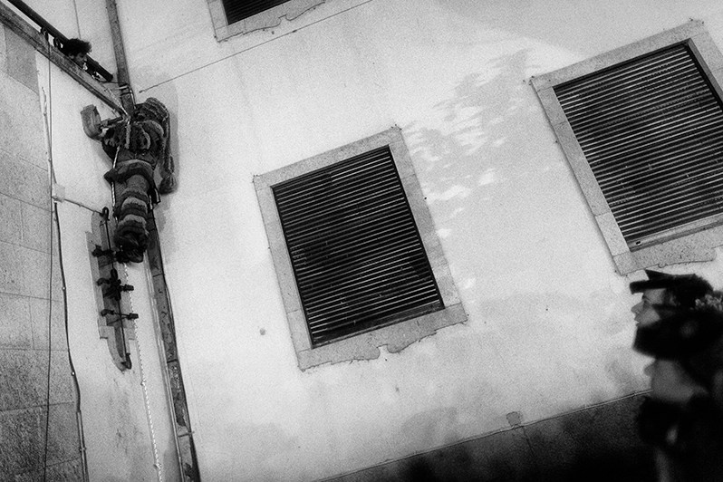 A “Careto” shows off his skills climbing a wall using a rope under the watchful eyes of younger “Caretos”, Macedo de Cavaleiros municipality, Bragança district, Trás-os-Montes region, Portugal. 2019