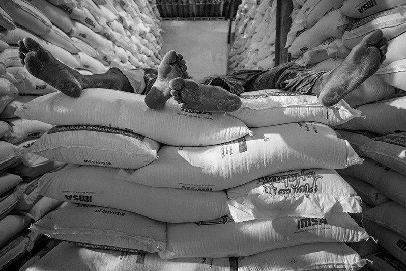 Workers rest after a day's work in a warehouse with sacks of flour, Carlos III street, Centro Habana district, Havana, Cuba. 2016