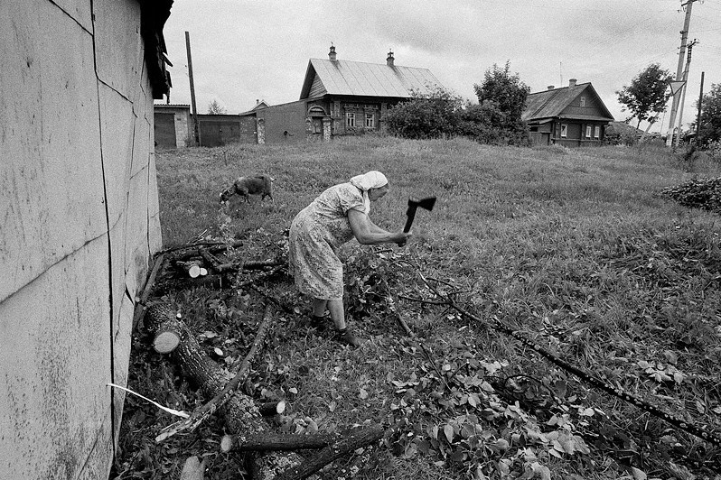 Женщина рубит топором ветки дерева, поваленного ветром на гараж, Семёнов, Нижегородская область, Россия. Июнь 2010
