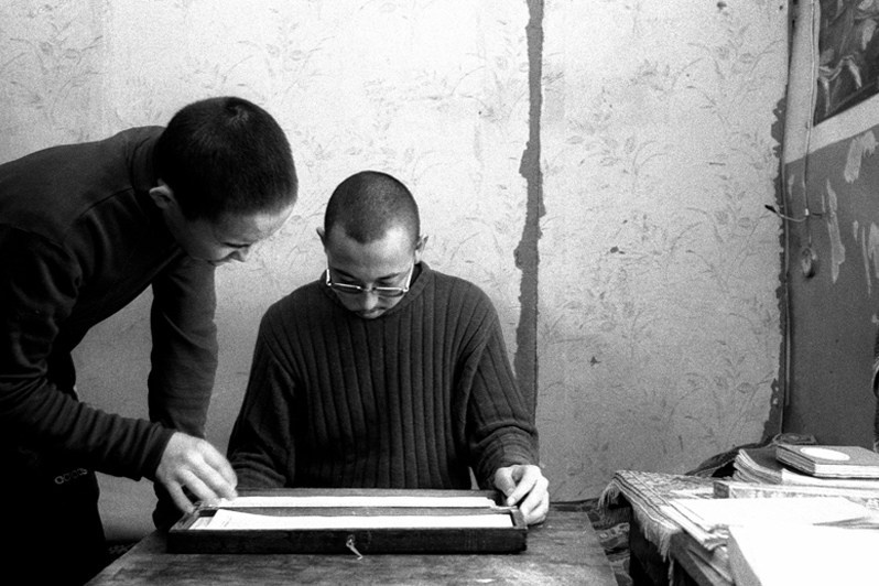 Buryat lama in his office examines the work of his students, Verkhnyaya Ivolga village, Buryatia, Russia. November 2001