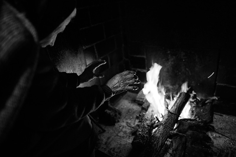 Woman warming her hands by the fire, Bragança district, Trás-os-Montes region, Portugal. 2017