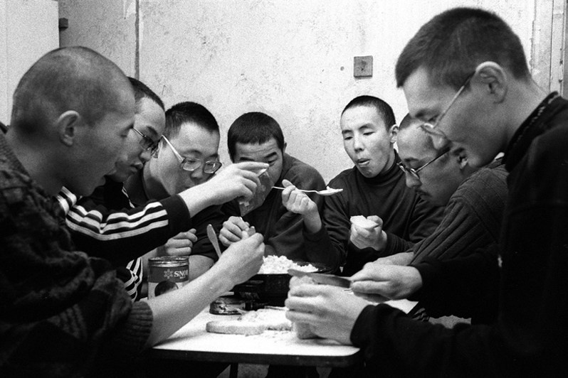 Buddhist monks in their room during a meal, Verkhnyaya Ivolga village, Buryatia, Russia. November 2001