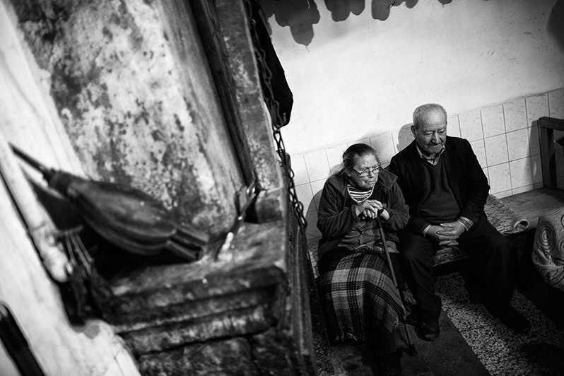 Couple warms up by the fireplace in their home, Vinhais municipality, Bragança district, Trás-os-Montes region, Portugal. 2019