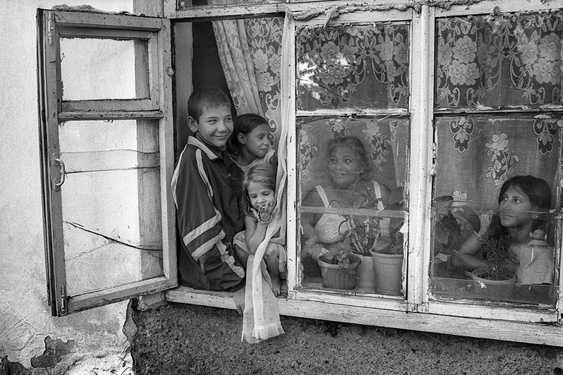 A family looks out of the window of their home onto the street, countryside around Khabarovsk, Russia. May 2014 © Oleg Klimov
