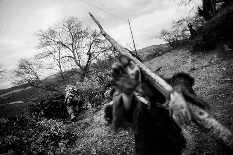 A “Máscaro” carries a stick to the bonfire, Vinhais municipality, Bragança district, Trás-os-Montes region, Portugal. 2019