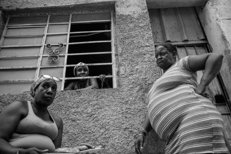 Three women talking at the front of a house in a neighbourhood in Havana, Centro Habana district, Havana, Cuba. 2019