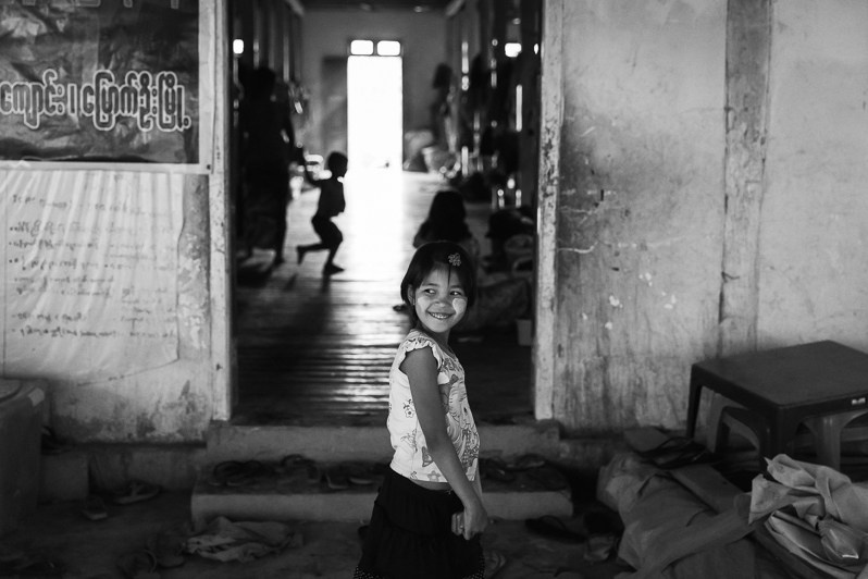 Arkanese IDP girl in front of one of the rooms used as a collective shelter for 400 IDPs that fled from 5 surrounding villages affected by the war, Chit Thaung Monastery IDP Camp, Mrauk-Oo, Rakhine state, Myanmar. February 2020