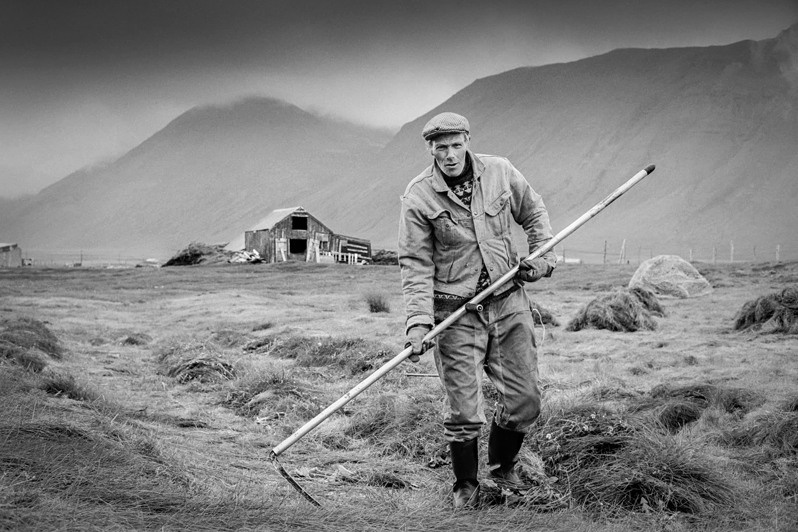 Þórarinn “Toti” Eiriksson of Finnbogastadir brandishes his scythe, Gjögur village, Árneshreppur district, Westfjords region, Iceland. 1993