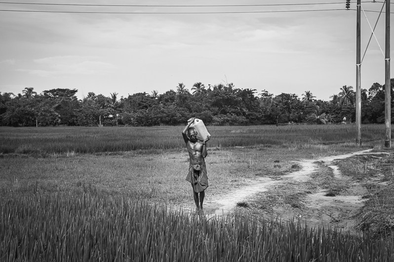 A Rohingya man carrying water to his village, Sittwe, Rakhine state, Myanmar. September 2019