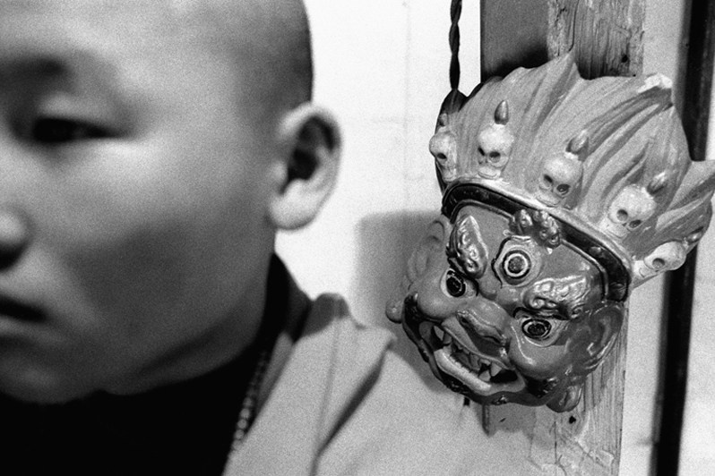 Portrait of a monk with a ritual mask used in a number of cult rituals, Verkhnyaya Ivolga village, Buryatia, Russia. November 2001