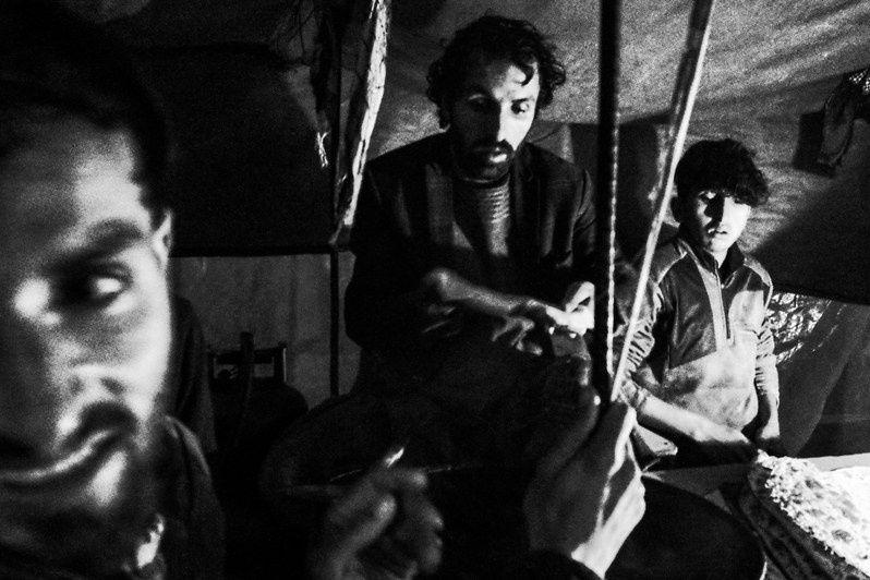 A man and his sons make filled flatbreads outside in the pouring rain, Kabul, Afghanistan. 2024