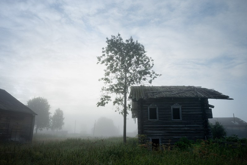 An abandoned wooden house in the morning fog, Vazhgort village, Udorsky district, Komi Republic, Russia. 2020
