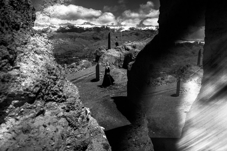 Khazar woman descends from the ruins of the red city to the farmland, Bamyan, Afghanistan. 2024