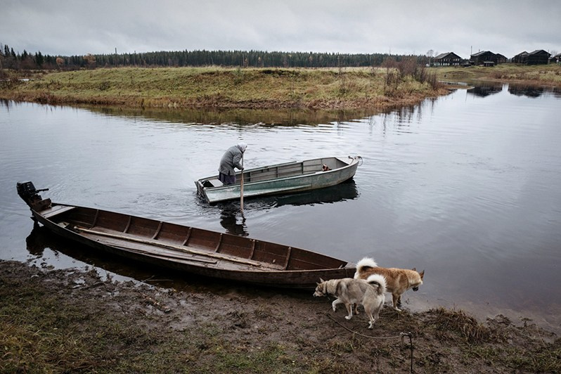 An old woman crosses a Sova River in a bot, near Sovpolye village, Mezensky district, Arkhangelsk region, Russia. October 2017