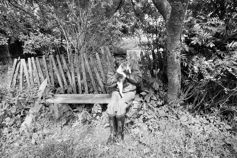 Нескрываемая улыбка жителя деревни в обнимку с котом, деревня Беляево, Кикнурский район, Кировская область, Россия. Июнь 2010