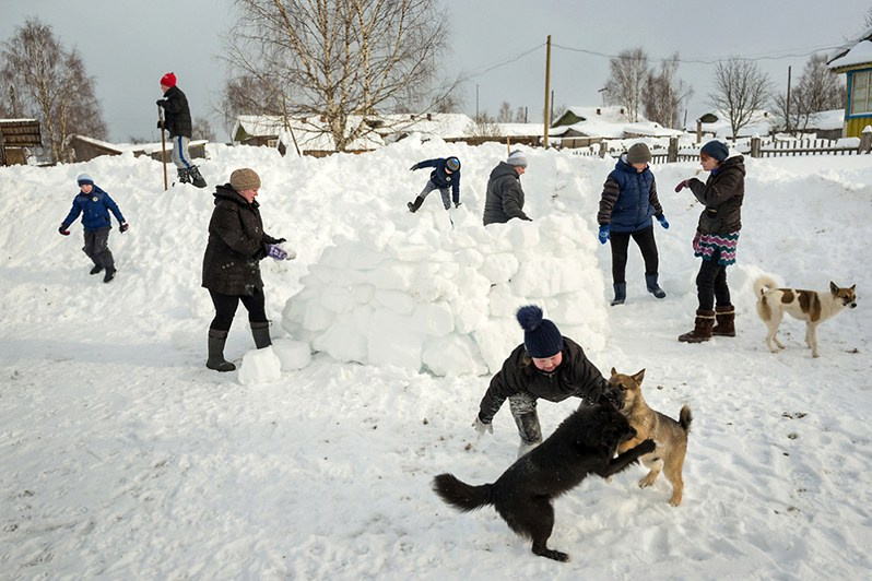 Kids fnd their teachers build a snow fortress in the schoolyard, Ust'-Chulasa settlement, Leshukonsky district, Arkhangelsk region, Russia. 2018