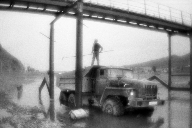 Рабочие загнали грузовик в реку и используют его в качестве платформы для покраски моста, село Чоя, Республика Алтай, Россия. Июнь 2021