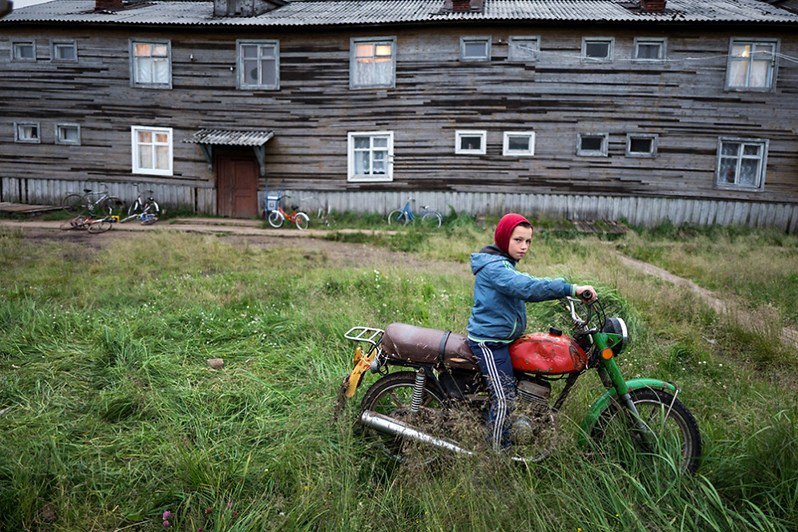 A boy rides his motorbike, Dolgoshchelye village, Mezensky district, Arkhangelsk region, Russia. 2019