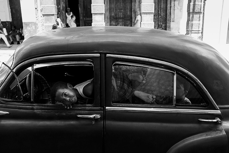 Portrait of a child spending time in the interior of a 1950s car, Centro Habana district, Havana, Cuba. 2022