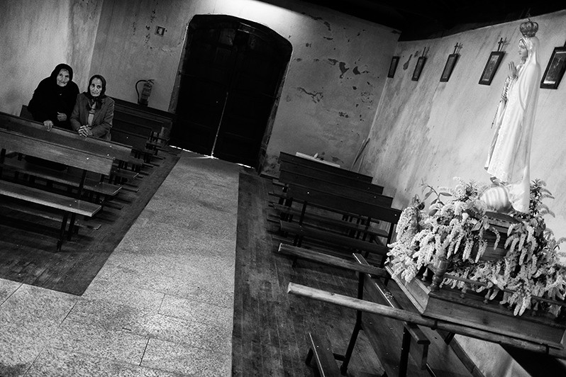 Two sisters wait for the beginning of mass, Bragança district, Trás-os-Montes region, Portugal. 2018
