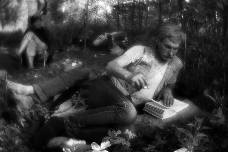 Саша читает книгу во время "сиесты" летним днем. Чтение — один из самых популярных способов проведения досуга в овраге, район Тропарёво-Никулино, Москва, Россия. 26 мая 2015