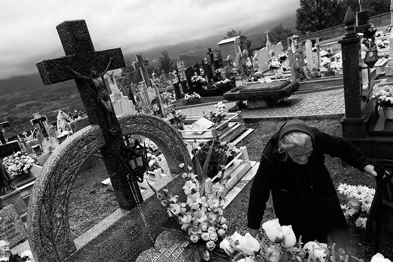 Woman takes care of the flowers on her family's grave, Montalegre municipality, Vila Real district, Trás-os-Montes region, Portugal. 2017