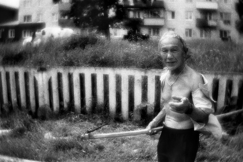 Школьный дворник прогоняет коров со школьного двора, Юрюзань, Катав-Ивановский район, Челябинская область, Россия. Июнь 2017