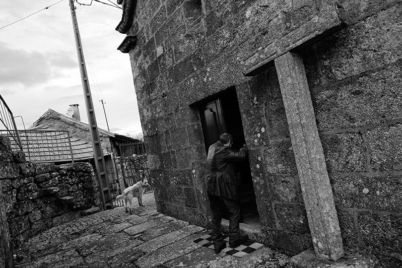 Dog follows owner as he walks to church, Montalegre municipality, Vila Real district, Trás-os-Montes region, Portugal. 2016