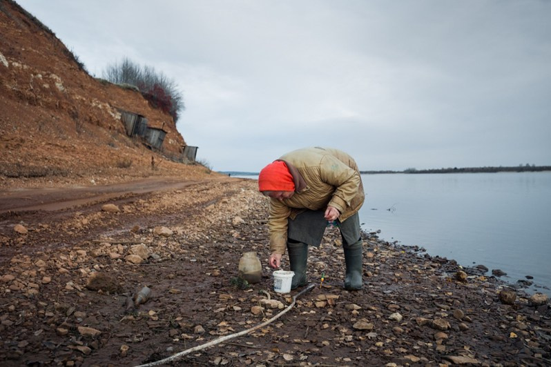Maria Nikolaevna Moiseenko (born 1939) fishes with a home-made fishing rod on the banks of Mezen River, Smolenets village, Leshukonsky district, Arkhangelsk region, Russia. 2021