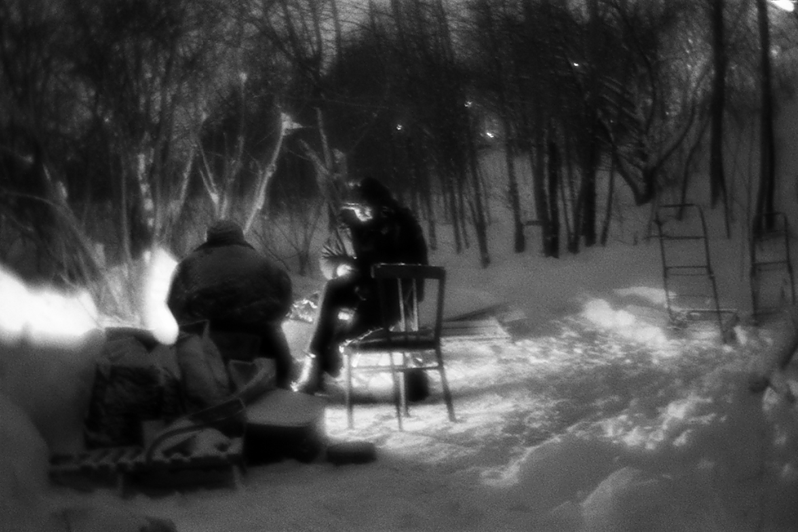 Костя и Наташа греются вечером у костра на своей кровати из поддонов и ковров, район Тропарёво-Никулино, Москва, Россия. 27 января 2016