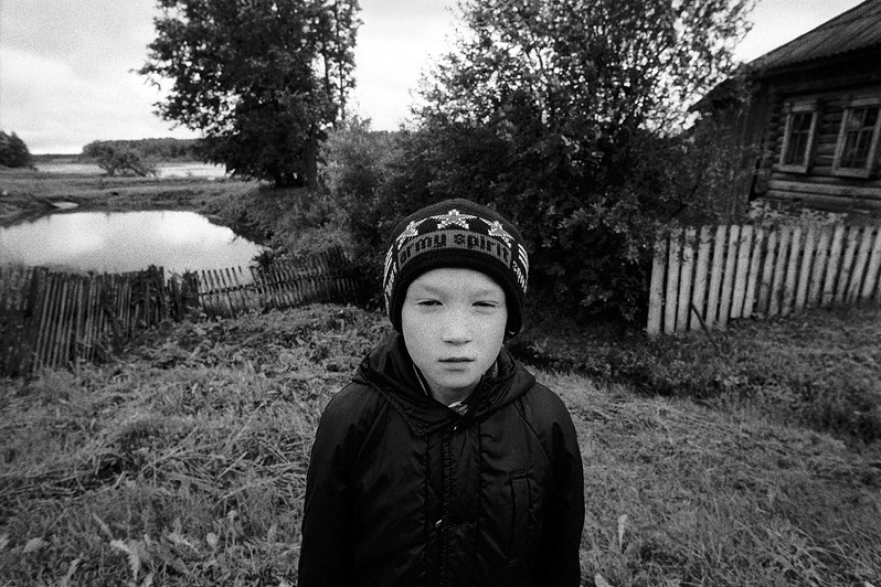 Деревенский мальчик в шапке с надписью "Армейский дух", не до конца проснувшись, идёт в школу, деревня Беляево, Кикнурский район, Кировская область, Россия. Июнь 2010
