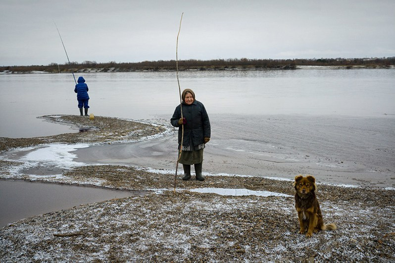 Maria Nikolaevna Moiseenko (born 1939) stands with a home-made fishing rod on the banks of Mezen River, near Smolenets village, Leshukonsky district, Arkhangelsk region, Russia. October 2017