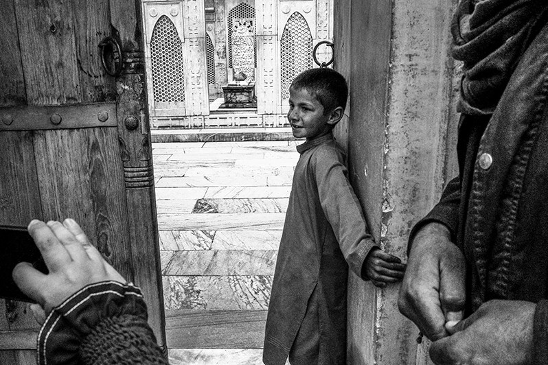 The son of the caretaker of Babur's palace opens the door for a foreign visitor, Chilsitun Road, Kabul, Afghanistan. 2024