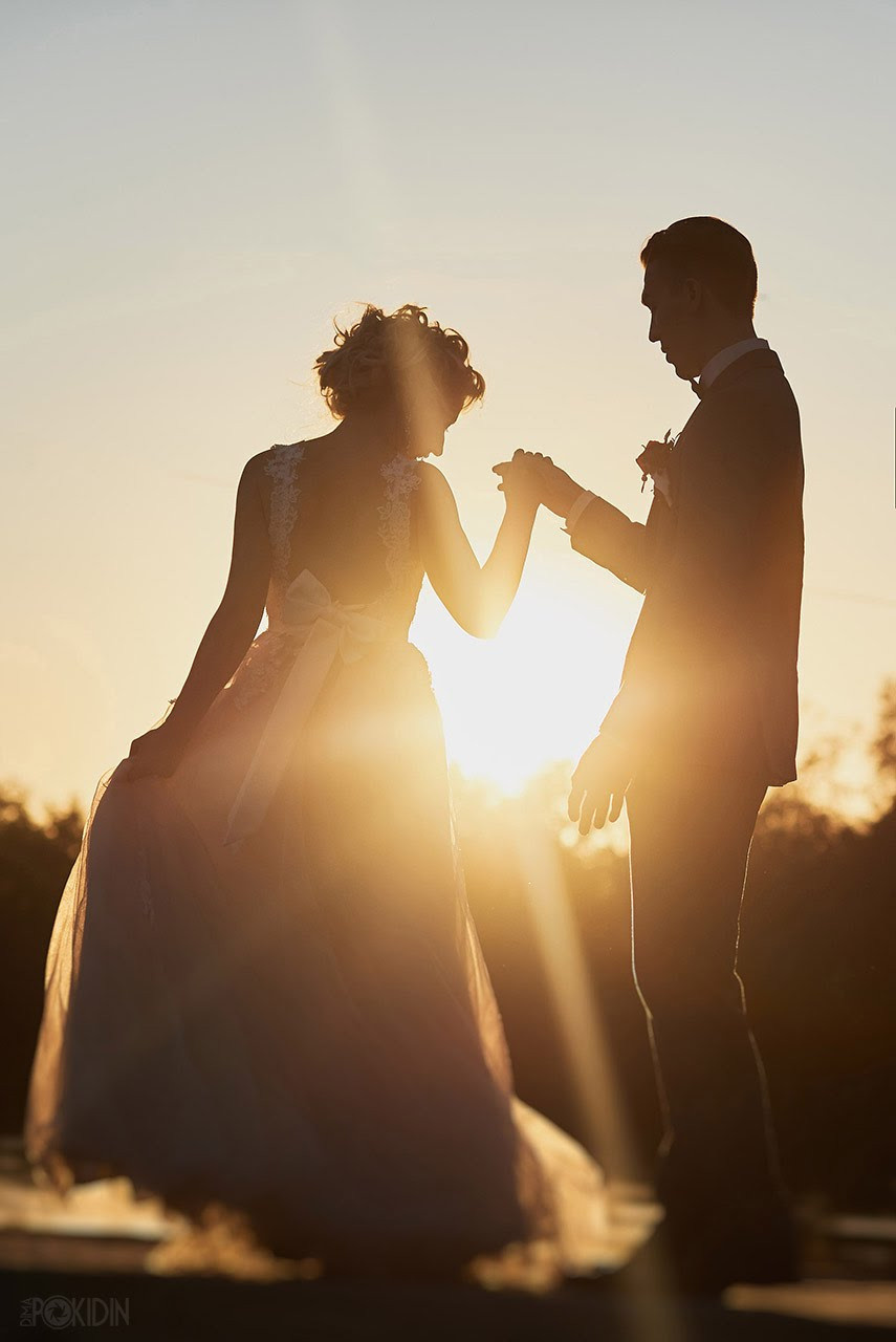 Жених и невеста держатся за руки на закате в Днепре.