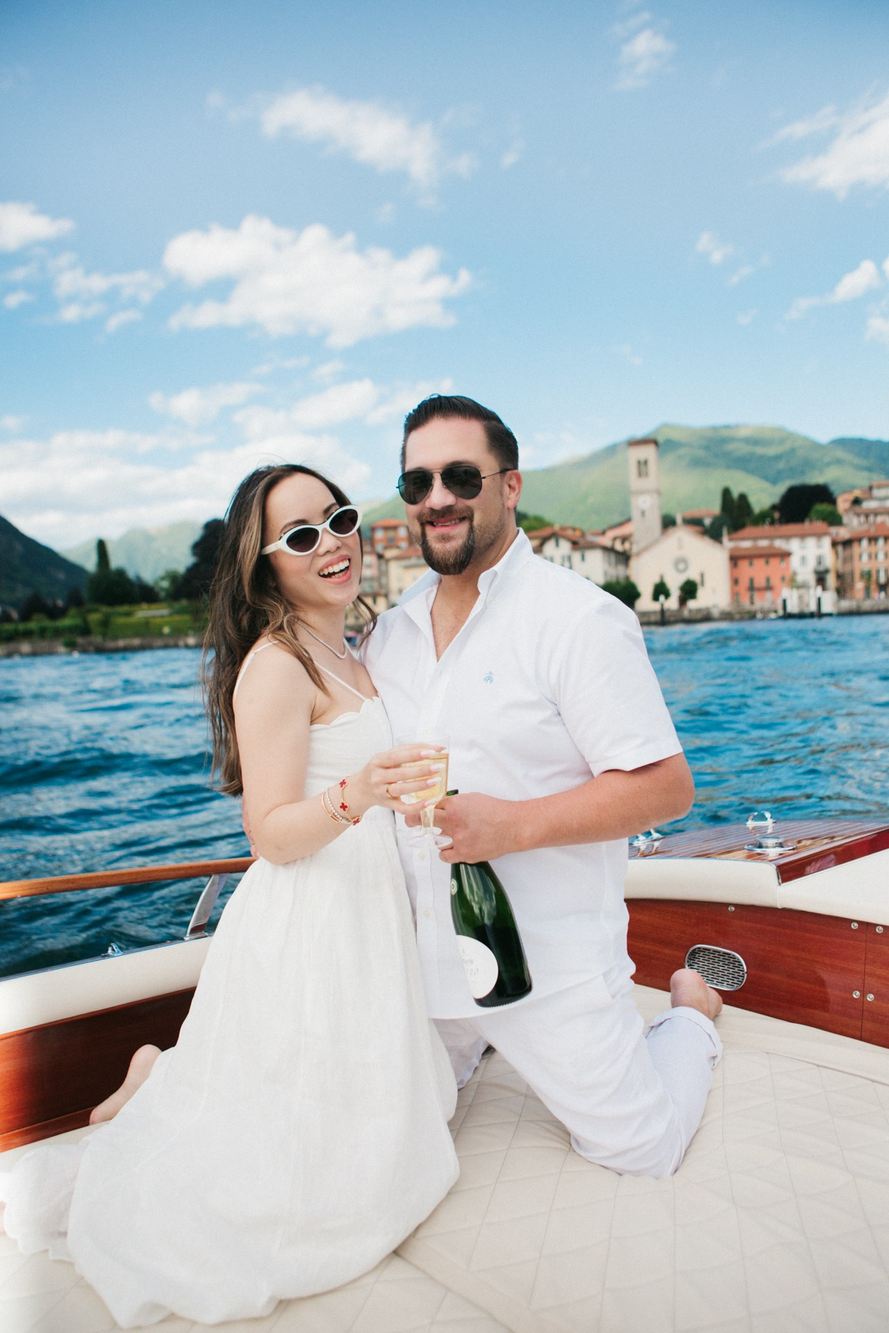 Stylish couple in all white sharing a romantic moment on a boat in Lake Como