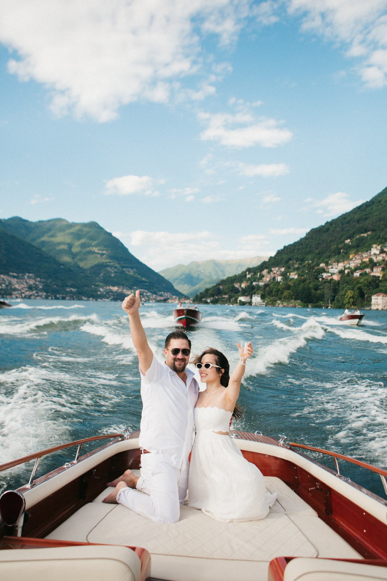 Stylish couple in white sharing romantic and joyful moments on Lake Como boat