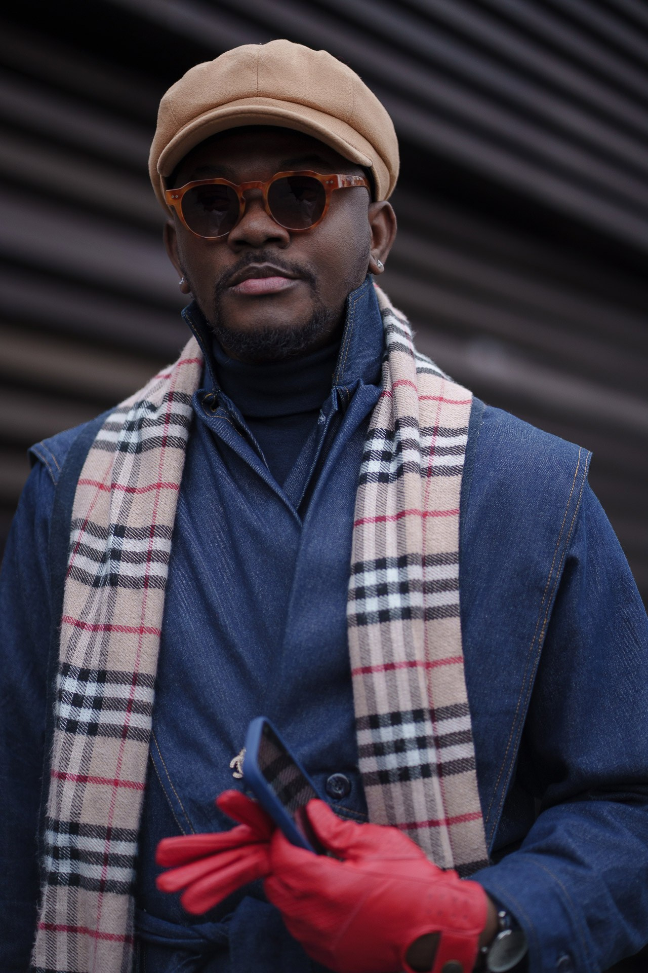 Man in blue coat and check scarf holding red gloves at Pitti Uomo