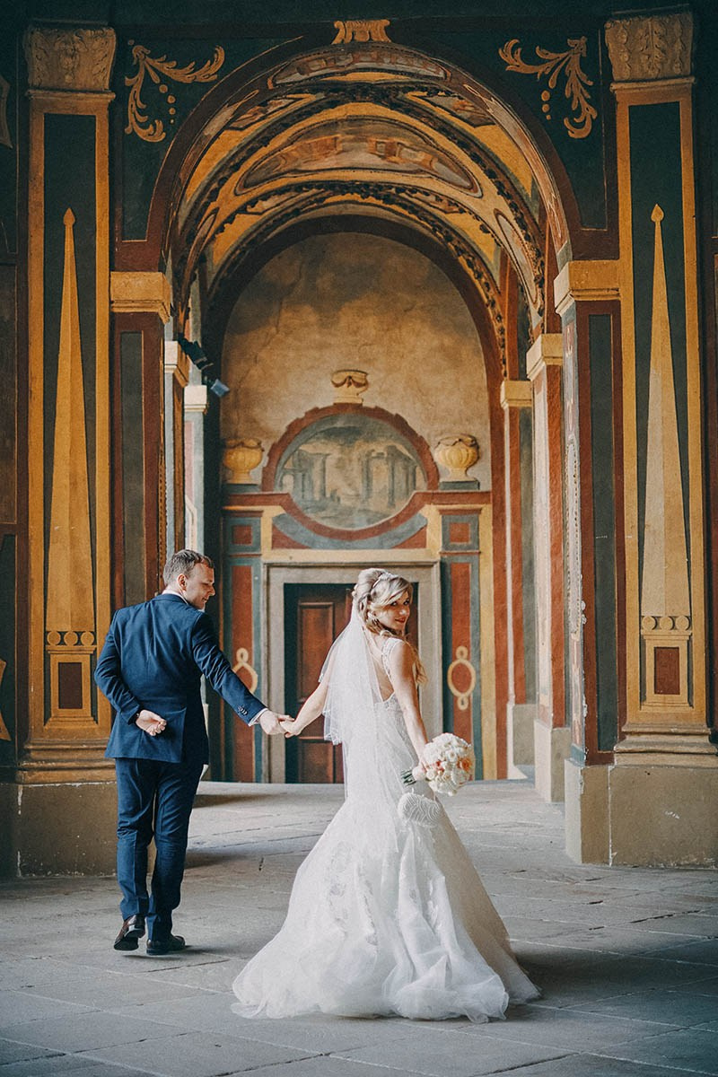 Newlyweds walk hand in hand through the historic Sala Terrena in the Ledebour Garden.