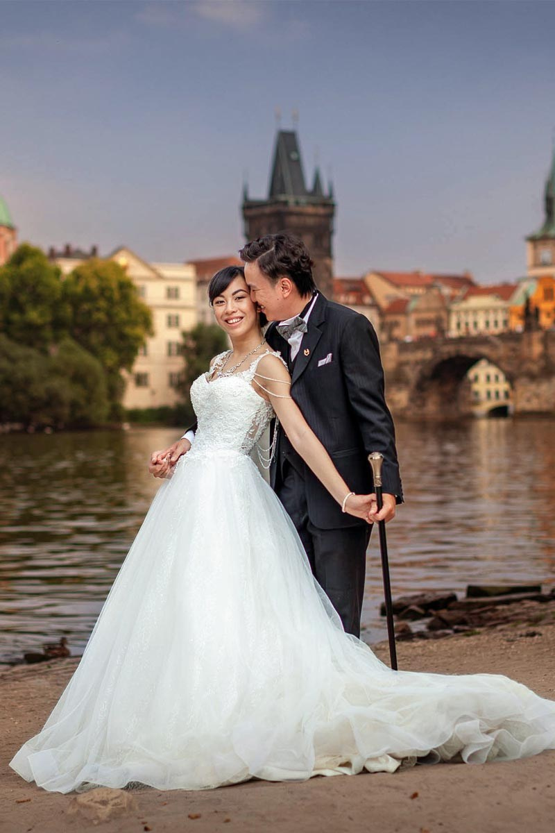 Stylish couple in an elegant embrace, near the riverside in Prague.