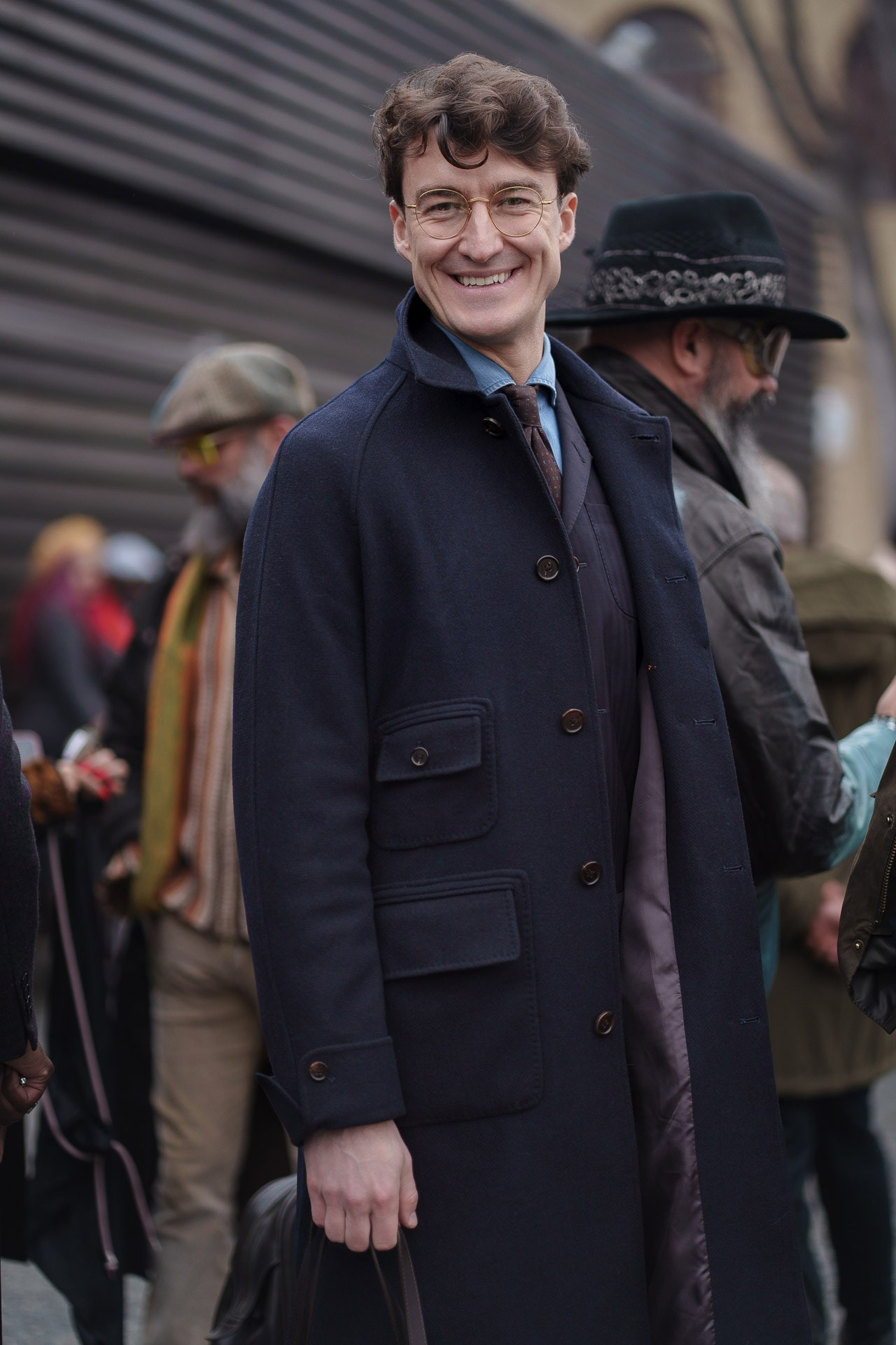 Man in dark coat smiling at camera during Pitti Uomo Florence